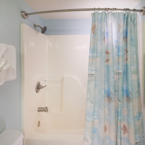 This guest bathroom featuring a spacious shower with a colorful curtain and soft towels for your comfort