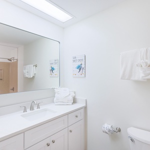Elevate your daily routine in the guest bath, surrounded by fresh towels and cheerful coastal decor