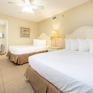Comfortable guest bedroom featuring two double beds, a bedside lamp, and decorative wall art, creating a relaxing vibe