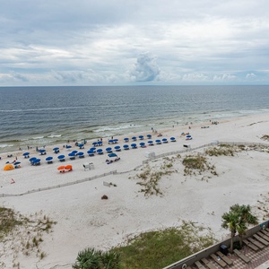 Enjoy beach and pool views from the balcony, with vibrant blue umbrellas dotting the sandy shore below