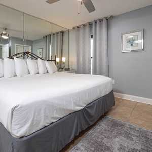 Relax in this cozy master bedroom featuring a plush king bed, elegant decor, and a mirrored accent wall for added charm