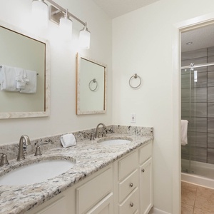 Master bathroom featuring dual sinks with stylish countertops, modern fixtures, and a walk-in shower with tile