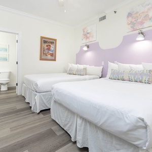 Relax in this elegant guest bedroom featuring two queen beds, soft linens, and cheerful decor for a restful stay