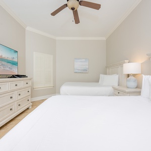 Guest bedroom featuring two comfortable queen beds and a large TV for entertainment