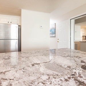 This kitchen features sleek stainless appliances, granite countertops, and a welcoming view of the adjacent living area
