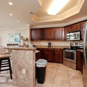 This kitchen features rich wooden cabinetry, stainless appliances, and a cozy bar area, perfect for casual dining