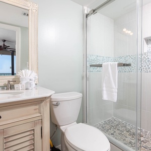 The master bathroom features a stylish vanity, large mirro,r and a walk-in shower, offering a refreshing retreat with a view
