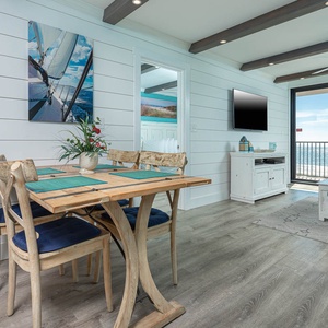 This inviting living area features a cozy seating arrangement, a TV, and a stunning beachfront view through large glass doors
