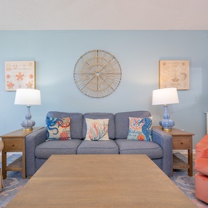 Cozy up on the sofa surrounded by sea-inspired pillows while soft lamps glow nearby in the living room