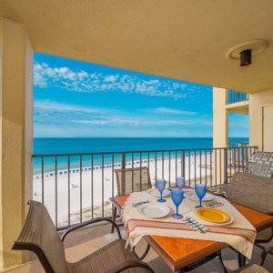 Dining table set for four with blue glasses overlooks the beach front, creating a perfect spot for meals with a view
