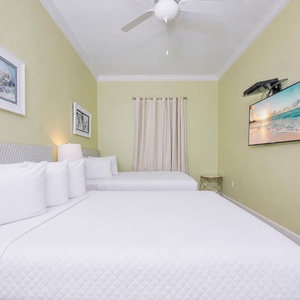 Rest comfortably in this inviting guest bedroom with two queen beds, soft linens, and a mounted TV