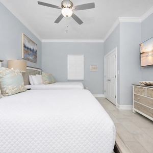 Experience restful nights in this guest bedroom with two queen beds, decorative pillows, and calming artwork