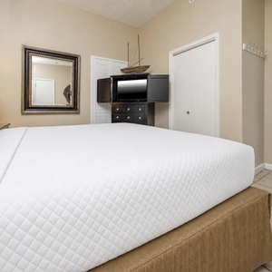 Relax in this inviting bedroom featuring a plush king bed, a stylish mirror, and a TV for your entertainment