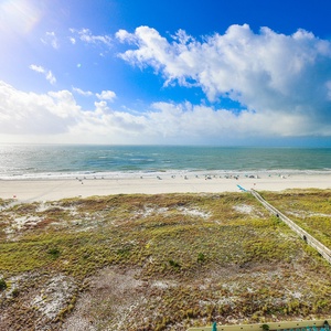 Stunning view of the beach with golden sand and beachgoers enjoying the sun beneath a vibrant blue sky