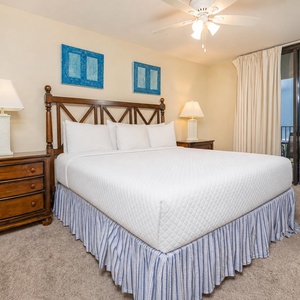 Master bedroom features a king bed with soft linens, wooden nightstands, and a sliding door leading to the beach balcony
