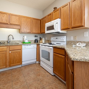 Cook and gather in the inviting kitchen with granite countertops and white appliances, perfect for meal preparation