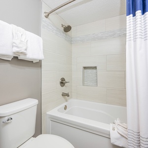 Master bathroom featuring a tub/shower combo, stylish tile accents, and neatly arranged towels for a refreshing experience