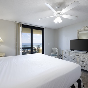 The master suite features a king bed, a TV, and a balcony with a view of the gulf, complemented by tasteful decor