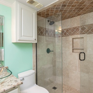 Guest bathroom featuring a glass walk-in shower, elegant granite countertops, and refreshing mint-green walls