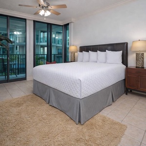 Master bedroom featuring a plush king bed, stylish decor, and large windows with a tropical view