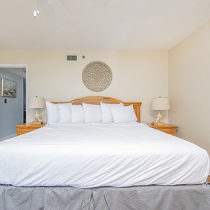 Master bedroom featuring a large king bed with white linens, bedside lamps, and a closet for ample storage