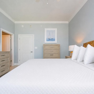 Tranquil guest bedroom featuring a king bed, a large TV, and coastal art that enhances the serene atmosphere