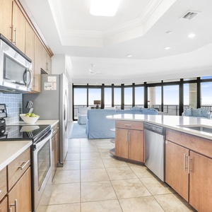 This modern kitchen features stainless appliances, sleek cabinetry, and a stunning beachfront view through expansive windows