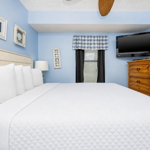 Relax in this inviting bedroom featuring a plush bed, cozy decor, and a TV for entertainment