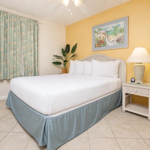 Cozy guest bedroom featuring a queen bed, tropical decor, and soft lighting for a restful stay