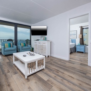 The living area features two comfortable chairs and a stunning beachfront view, perfect for relaxation