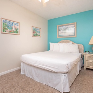 This guest bedroom features a comfortable bed, colorful artwork, and a charming lamp, perfect for a restful getaway
