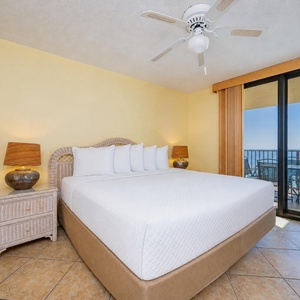 King bed in the master suite invites restful nights with balcony doors framing shimmering gulf waters