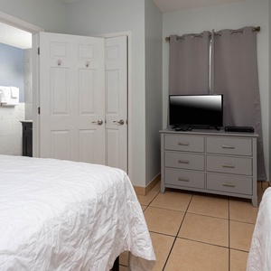 Inviting guest room featuring two cozy queen beds, a TV, and easy access to a stylish bathroom with fresh towels