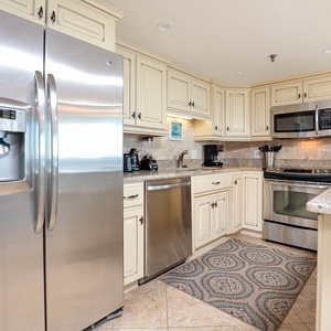 The kitchen features cream cabinetry, granite countertops, stainless appliances, and a decorative area rug for added charm