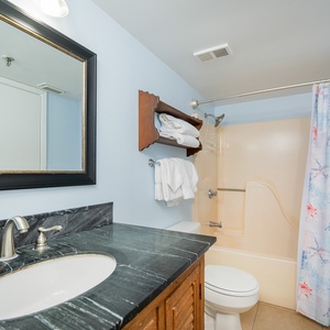 Refreshing bathroom features a tub and shower combo with coastal-themed curtain and plush towels