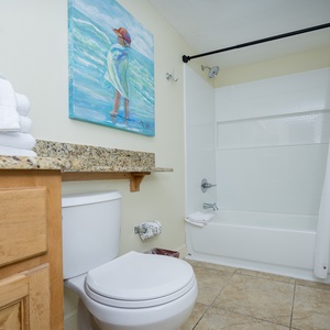 This bathroom features a clean design with a tub/shower combo, granite countertop, and fresh towels for your convenience