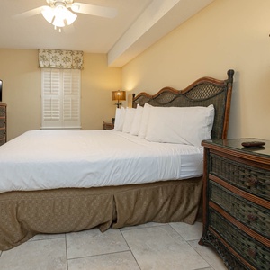 Guest bedroom featuring a king bed with plush bedding, a flat-screen TV, and charming wicker furniture accents