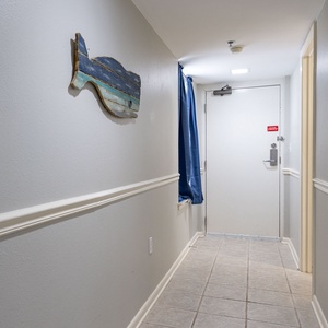 Welcoming hallway featuring a decorative wooden whale and a blue curtain, leading to the entrance door of the vacation rental