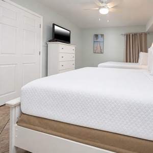 Relaxing guest bedroom featuring two comfortable double beds, a TV, and coastal-themed décor