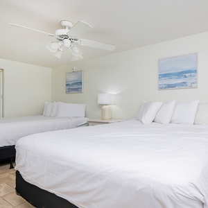 This guest bedroom features two queen beds, soft linens, and coastal artwork, creating a serene and inviting atmosphere