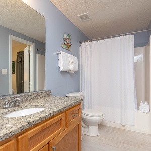 Enjoy the spacious guest bathroom with a granite countertop, ample towels, and a relaxing tub-shower combination