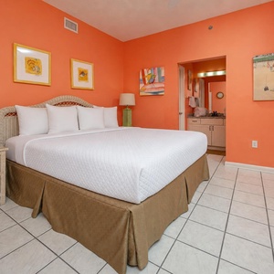 Vibrant orange walls enhance the inviting atmosphere of the master bedroom, featuring a plush king bed and stylish decor