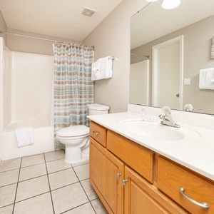 Refresh in this guest bathroom featuring a spacious vanity, tiled floor, and a relaxing tub with a shower curtain