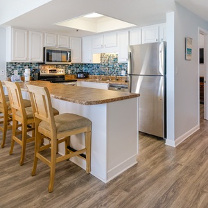 Bright and inviting kitchen features stainless appliances, a spacious countertop, and seating for casual dining