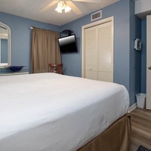 Bright blue walls complement the king bed, while a wall-mounted TV and tasteful decor enhance the inviting atmosphere