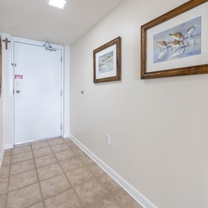 Welcoming entryway features tiled flooring, framed artwork, and a door leading to the main living area