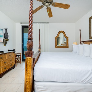 Relax in this inviting master suite with a king-size bed, tropical decor, and a view of the beachfront balcony