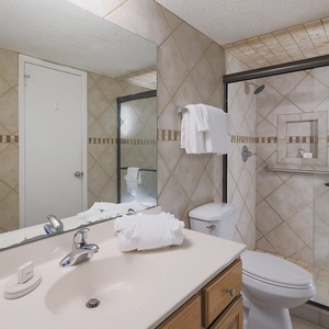 The bathroom features an elegant walk-in shower, a stylish vanity, and neutral tile accents throughout, for a refreshing stay