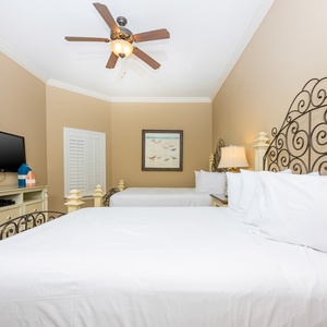 This guest bedroom features two comfortable full beds, a flat-screen TV, and soft beige walls, creating a relaxing atmosphere