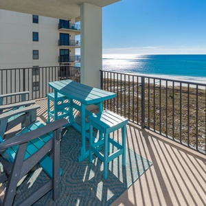 Balcony with turquoise furniture offers a serene view of the sparkling gulf and white sand beach below